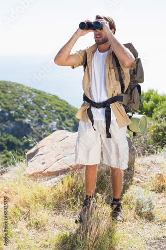 Handsome hiker looking through binoculars