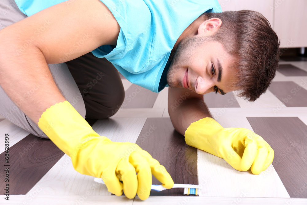 Young man cleaning floor in room Young man cleaning floor in room