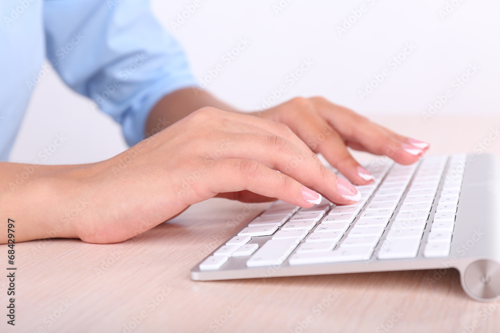 Female hands typing on keyboard, close-up, on light background Female hands typing on keyboard, close-up, on light background