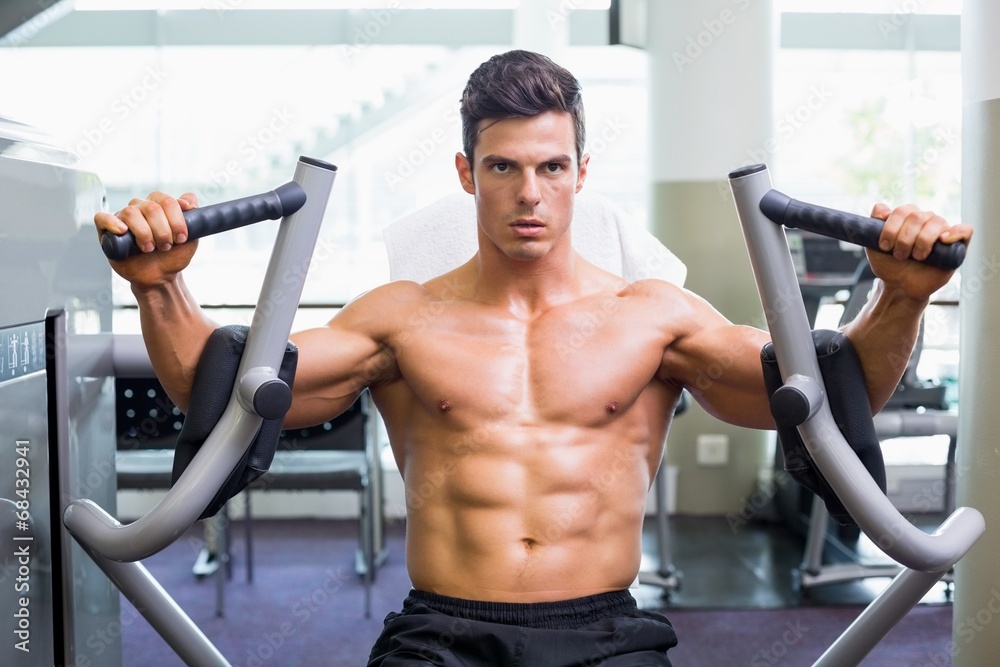 Muscular man working on fitness machine at the gym Muscular man working on fitness machine at the gym