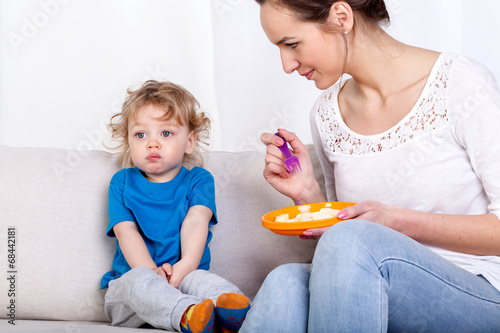 Mother feeding child on couch