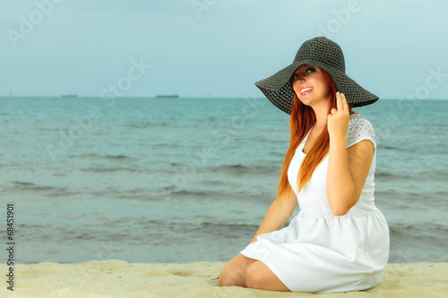 Beautiful redhaired girl in hat on beach, portrait