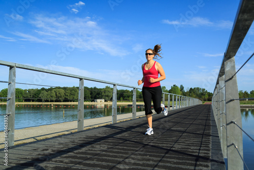 Woman running on a boardwalk at a lake.