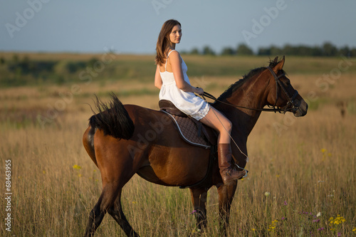 Girl in white dress riding on a horse