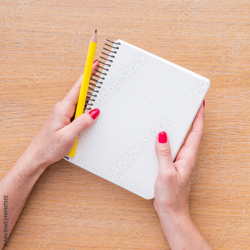 Women hand holding new notebook on wooden background
