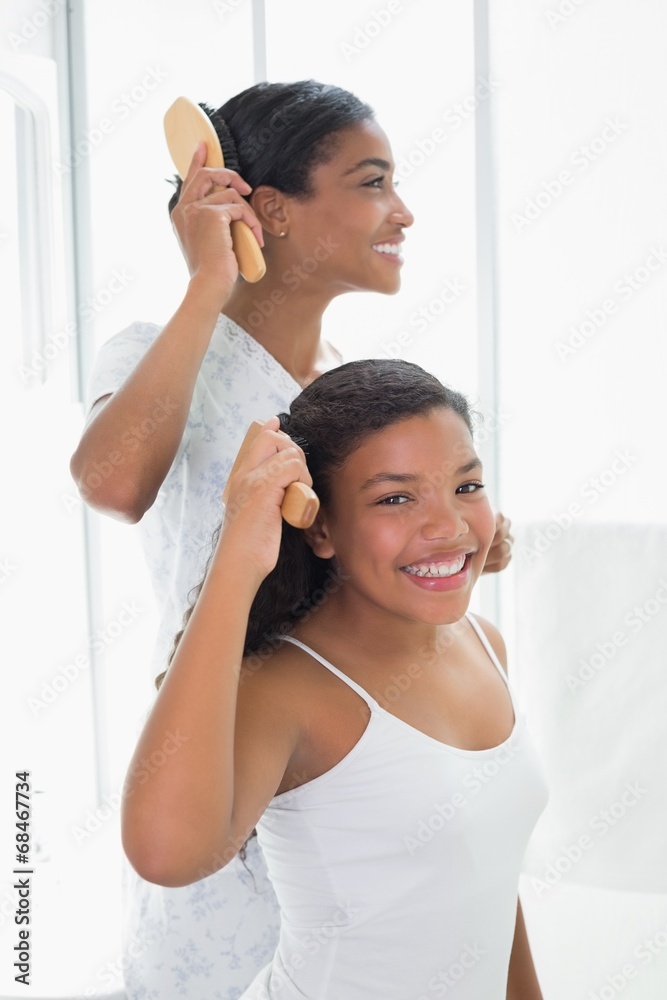 Mother and daughter brushing their hair together Mother and daughter brushing their hair together