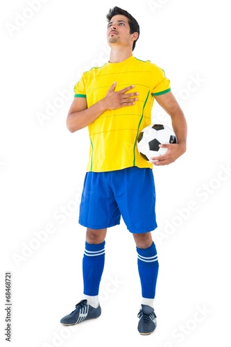 Football player in yellow with ball listening to anthem