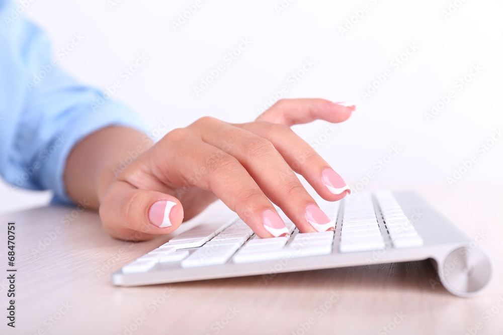 Female hands typing on keyboard, close-up, on light background Female hands typing on keyboard, close-up, on light background