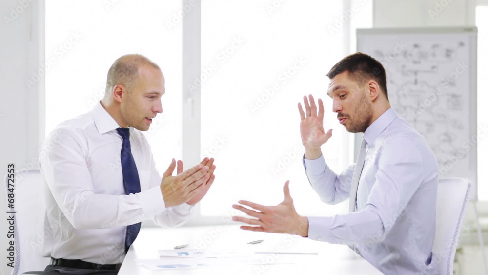 two serious businessmen with charts in office two serious businessmen with charts in office