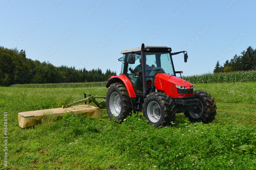 Organic farmer in tractor mowing clover field with rotary cutter Organic farmer in tractor mowing clover field with rotary cutter