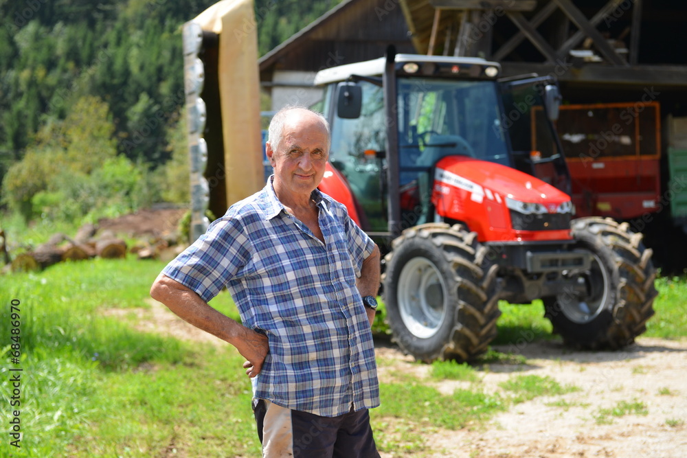Fototapeta premium Proud farmer standing in front of his red tractor