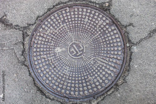 Manhole with metal cover in cracked asphalt surface