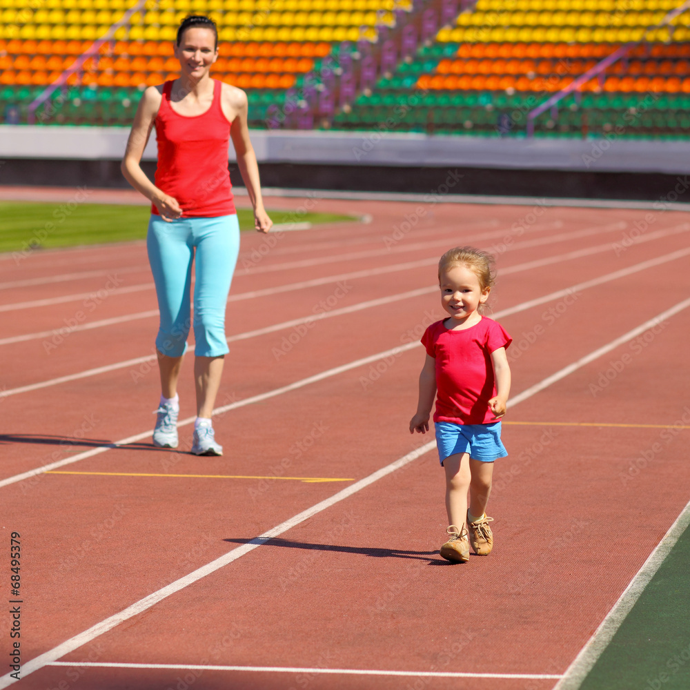 Mother & little daughter running around the stadium. 