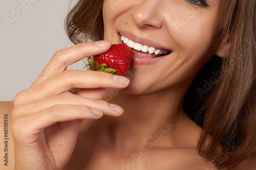 Beatiful girl with perfect smile eat healthy food red strawberry