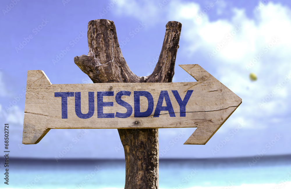 Tuesday wooden sign with a beach on background