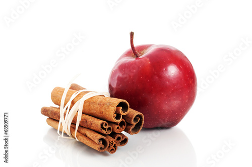 Red apple and cinnamon sticks over white background