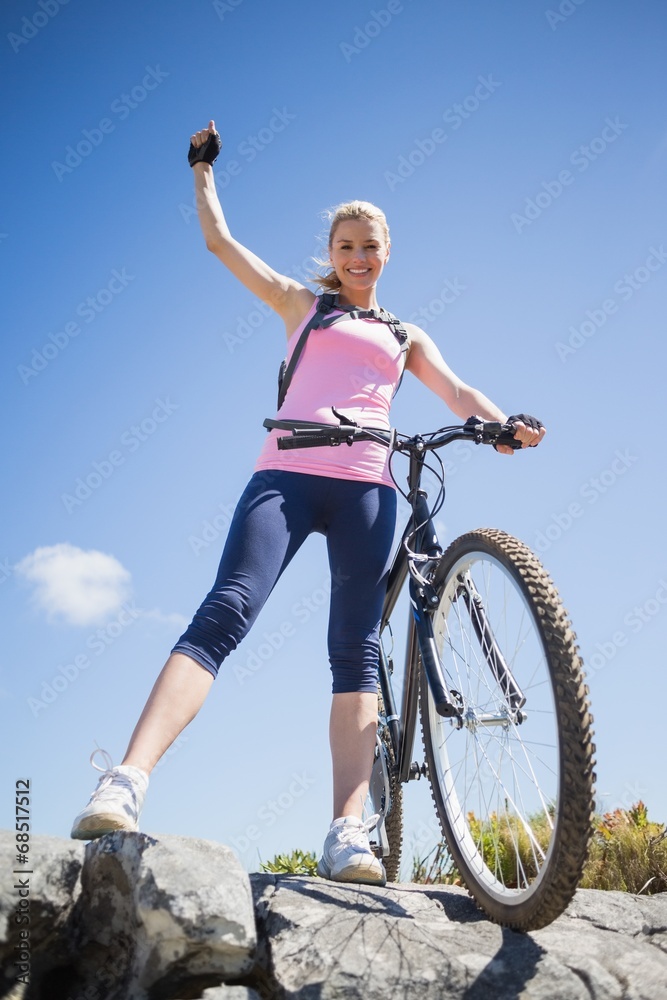 Fit pretty cyclist on a rocky terrain smiling at camera Fit pretty cyclist on a rocky terrain smiling at camera