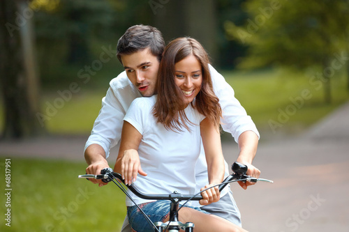 Happy couple cycling in the summer park