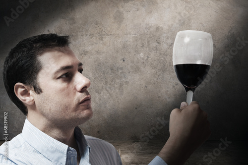Young man looking at a glass of wine photo