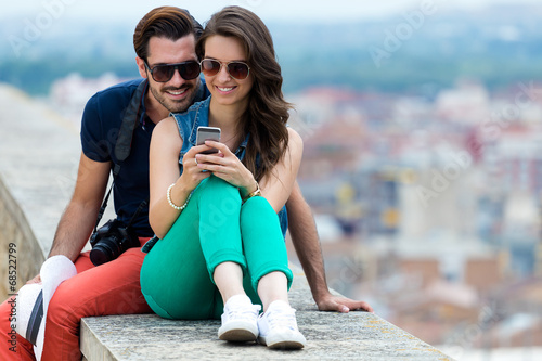 Young couple of tourist in town using mobile phone.