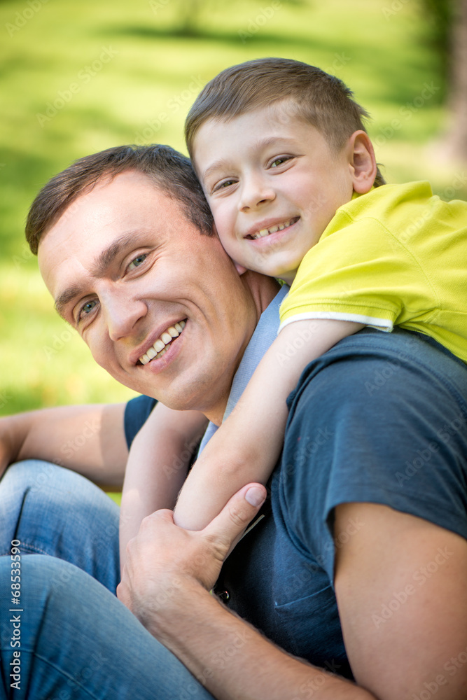 Smiling happy father and son hugging in the park Smiling happy father and son hugging in the park