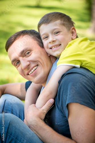 Smiling happy father and son hugging in the park