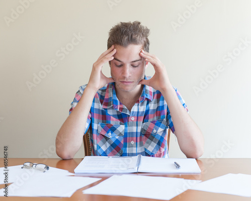 Fotografie Young adult studying ,feeling frustrated, in a messy desktop