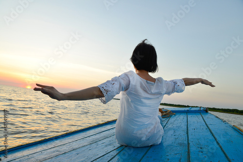 healthy middle aged woman traveling by wood boat at sunset