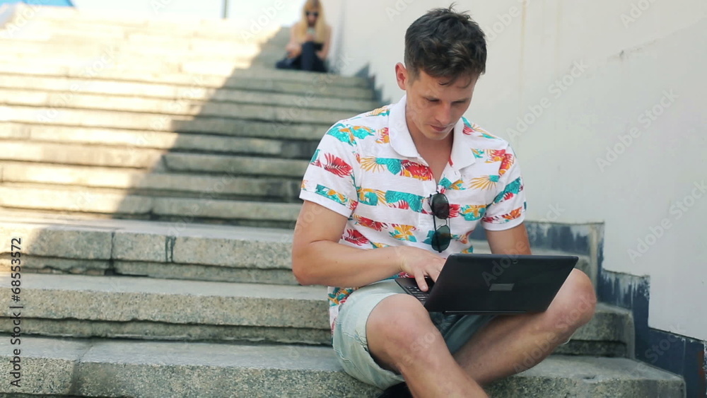 Trendy man with modern laptop sit on stairs in the city Trendy man with modern laptop sit on stairs in the city