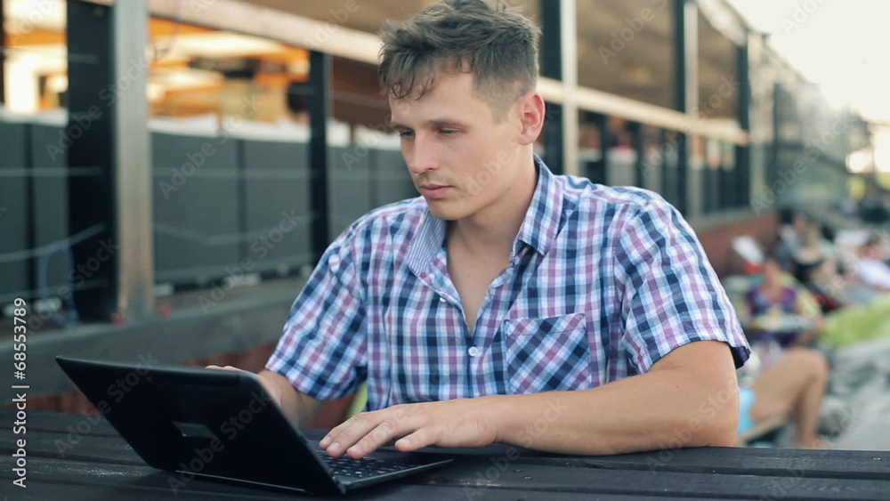 Young man working on laptop in outdoor city bar Young man working on laptop in outdoor city bar