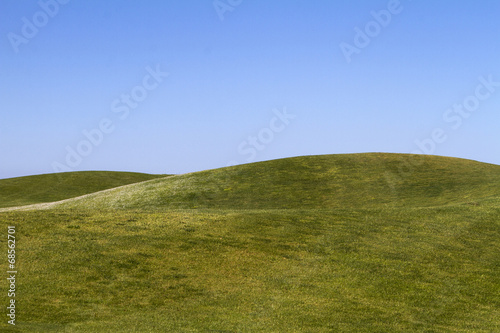 Photographie View of bare green hills with a blue sky.