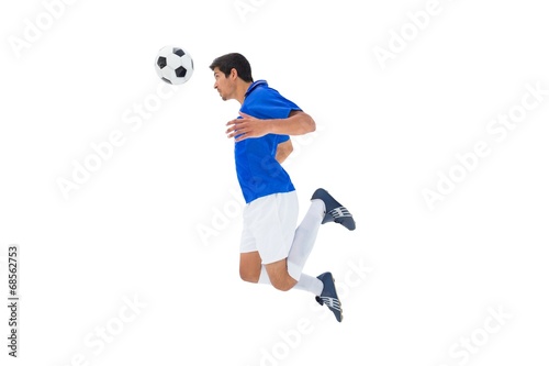 Fototapeta Naklejka Na Ścianę i Meble -  Football player in blue jumping to ball