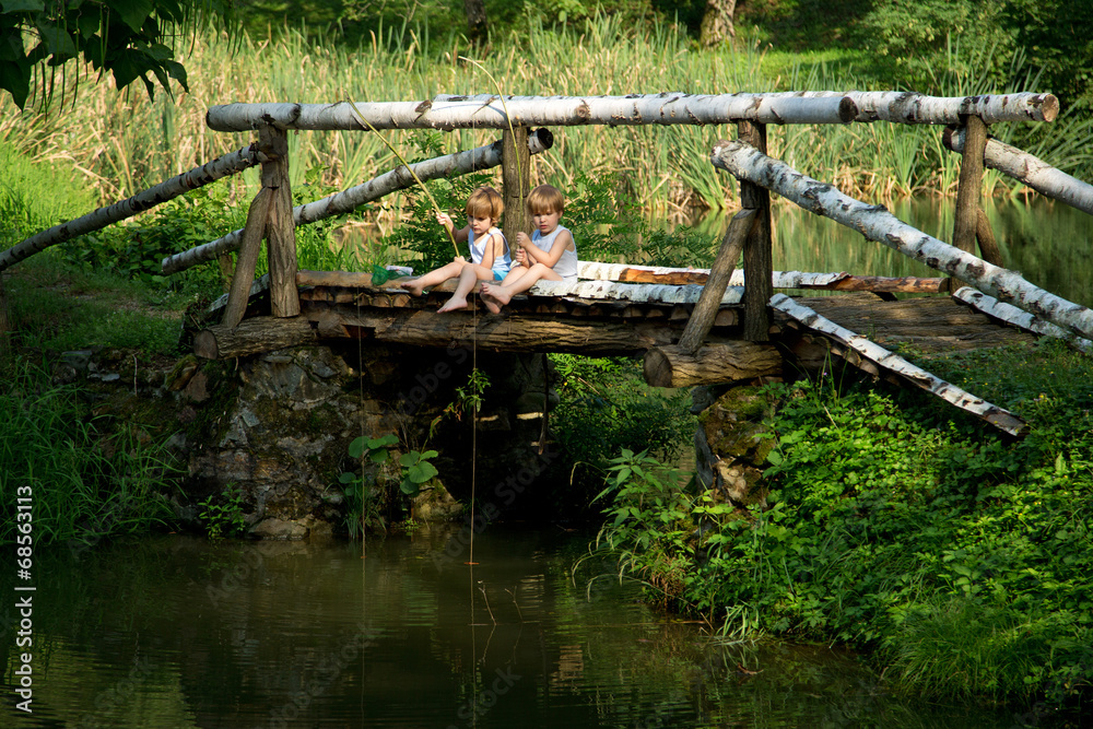 Twin Brothers Fishing from the Edge of Wooden Bridge at Summer Twin Brothers Fishing from the Edge of Wooden Bridge at Summer