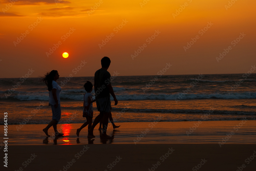 silhouette of family walking along the coast at the sunset