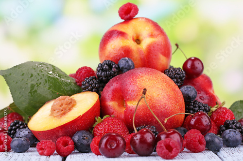 Fototapeta Naklejka Na Ścianę i Meble -  Peaches with berries on table on natural background