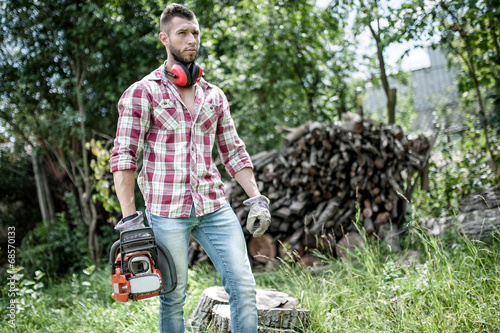 lumberjack or woodcutter moving and looking with chainsaw photo