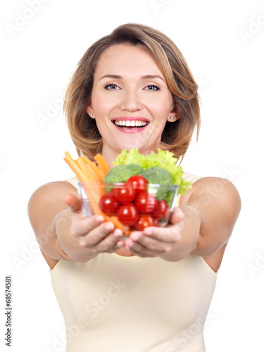 Portrait of a young smiling woman with a plate of vegetables.