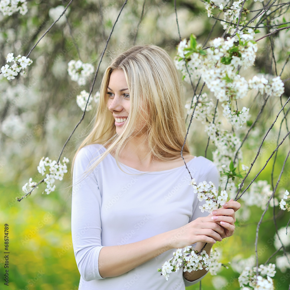 Happy smiling woman in blooming garden in spring - obrazy, fototapety, plakaty 