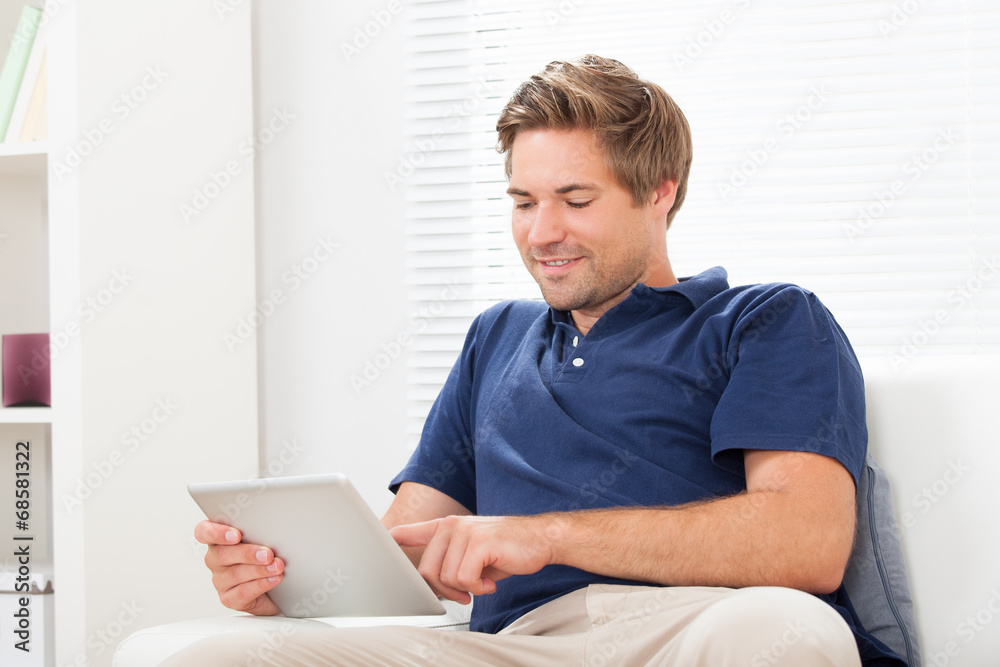 Man Using Digital Tablet On Sofa At Home Man Using Digital Tablet On Sofa At Home