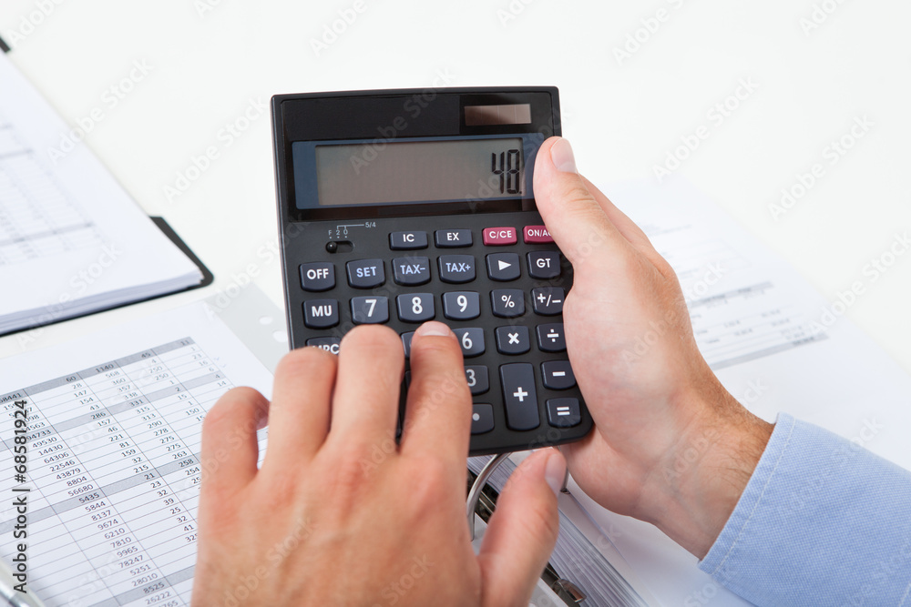 Businessman Calculating Tax In Office Businessman Calculating Tax In Office