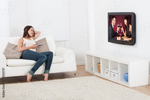 Woman Watching Television While Lying On Sofa