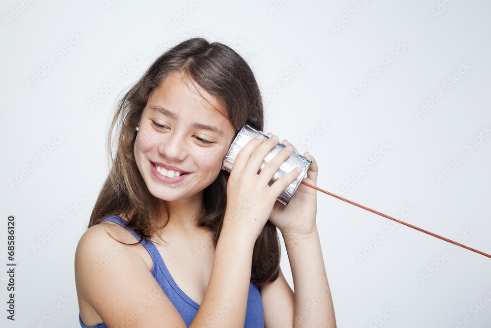 Happy smiling child using a can as telephone against gray backgr