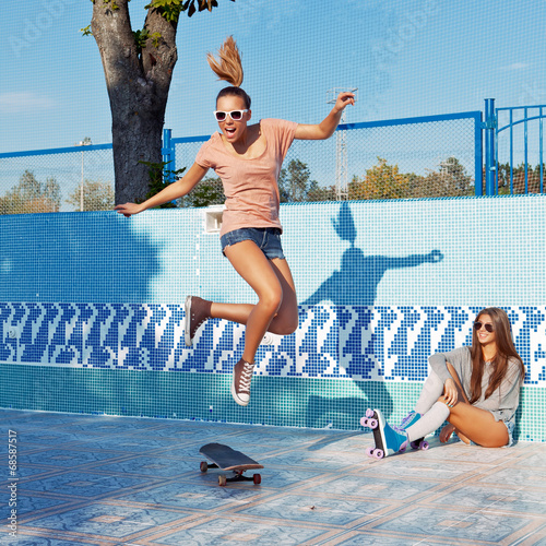 two beautiful young girls in sunglasses in an empty pool