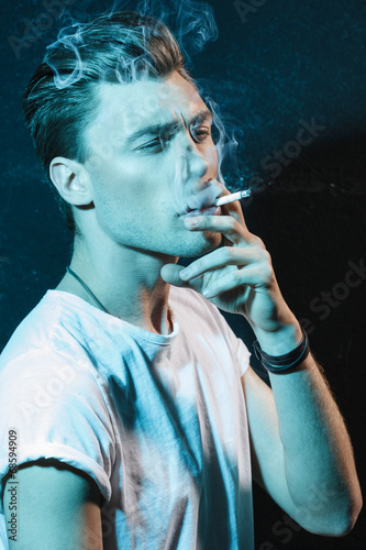 Handsome young man smoking cigarette