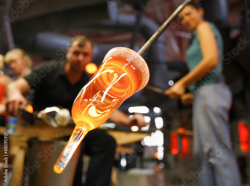 Glass furnace. Man holding a red-hot glass , close up