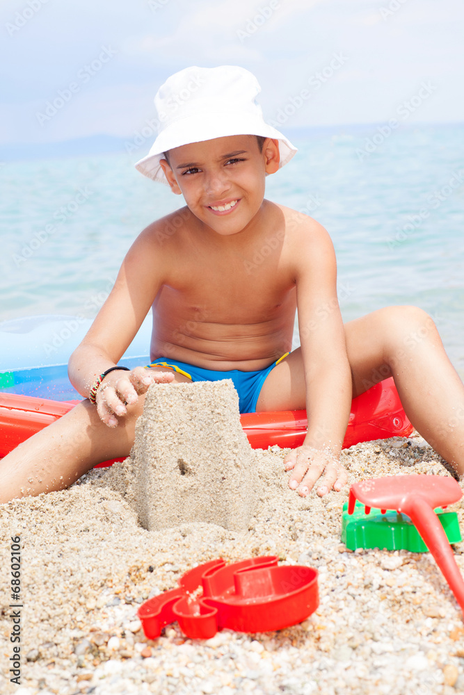 Little boy at tropical beach making sand castle Little boy at tropical beach making sand castle