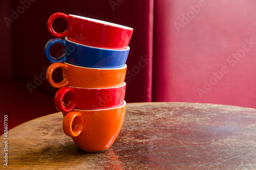 colorful coffee cups stacked on an old wooden table in a cafe