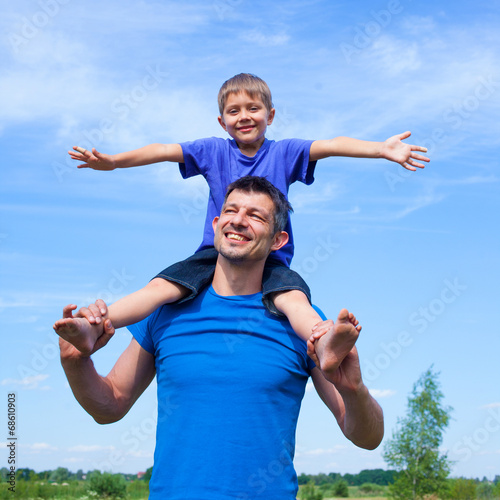 Happy father with son outdoors against sky