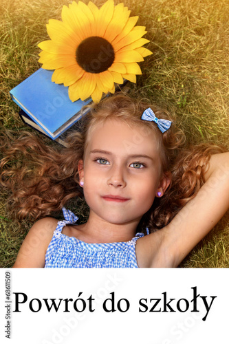 Uczennica - dzieczynka leży na trawie z kasiążką