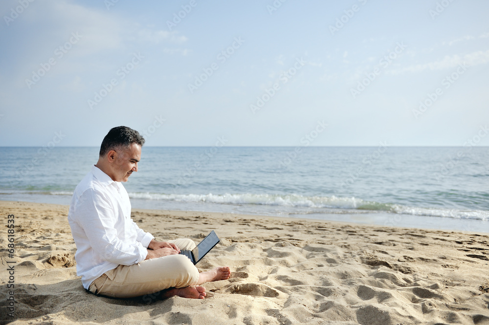 man with laptop computer working on the beach
